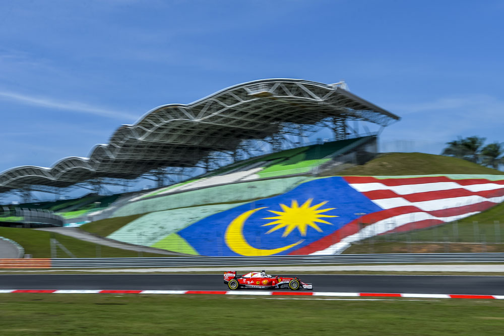 Fernando Alonso zooming past the Malaysian flag in Sepang